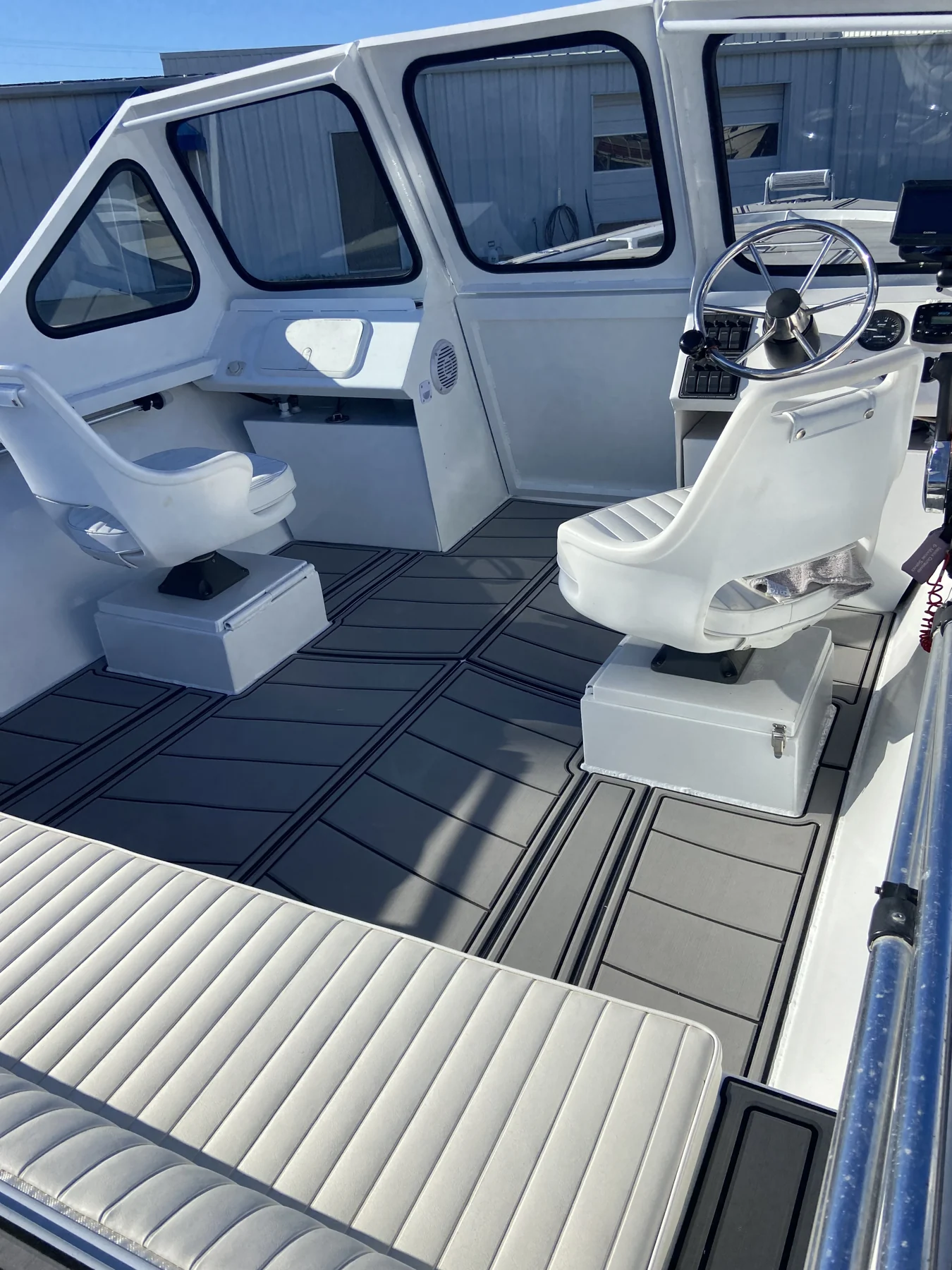 Gray flooring fitted through the cockpit of a white cabin boat.