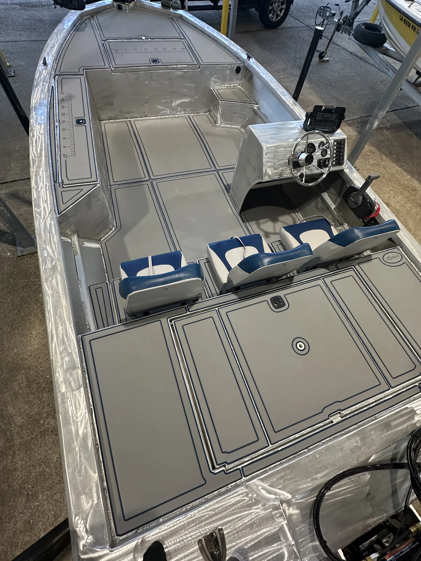 Gray flooring around seats and hatches inside an aluminum fishing boat.