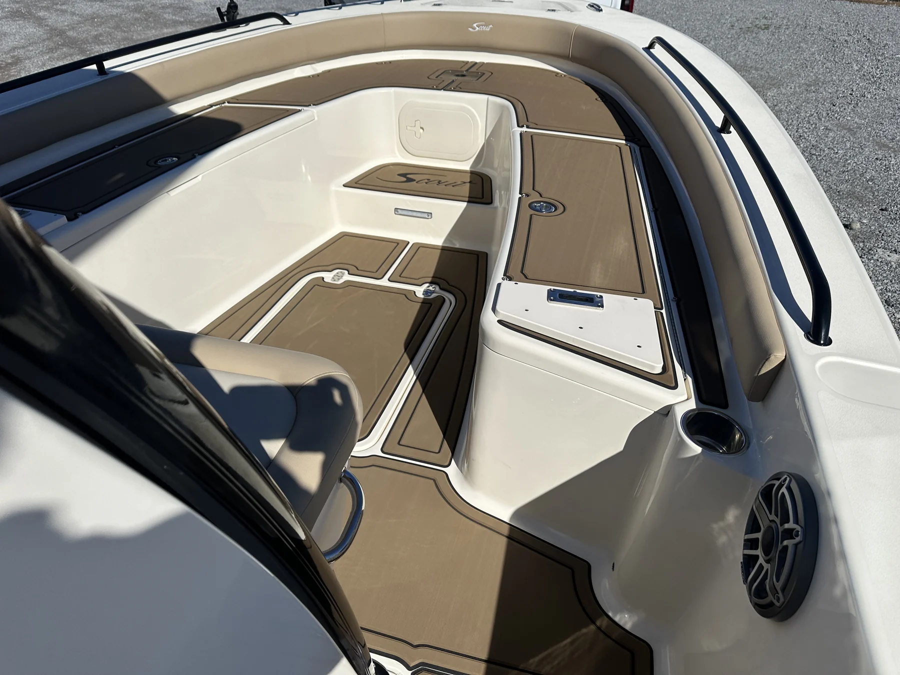 Custom tan marine flooring precisely fitted around the bow seats and hatches of a Scout boat.