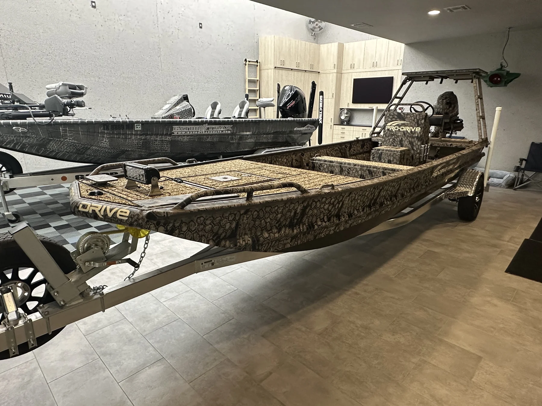 Camouflage fishing boat with coordinated tan flooring in a workshop.
