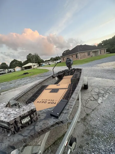 Camouflage hunting boat with fitted tan flooring outdoors.